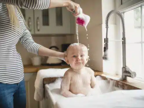 Women soaking baby in tub with hot water from water heater