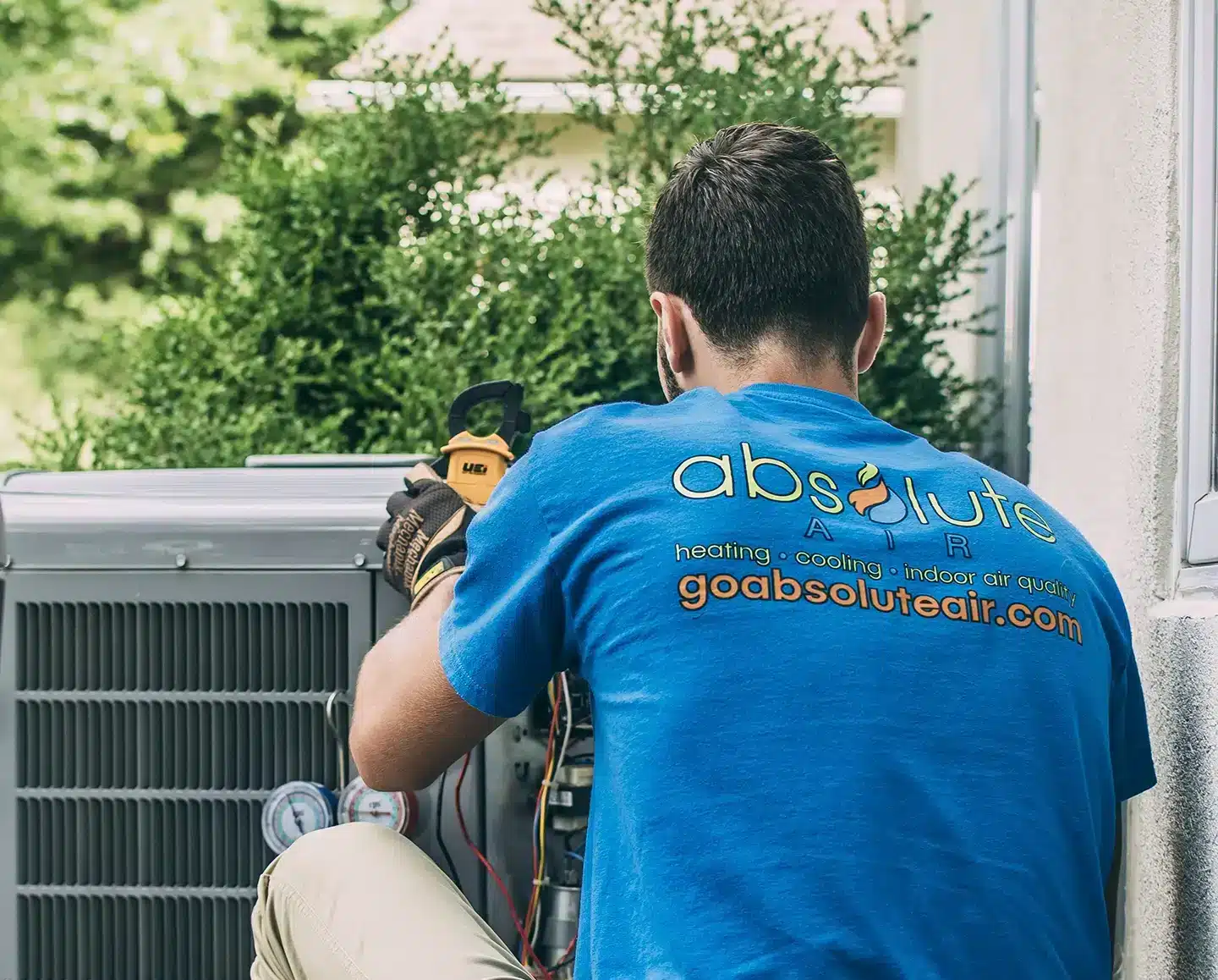Absolute Heating & Air employee conducting AC service outside of customers home