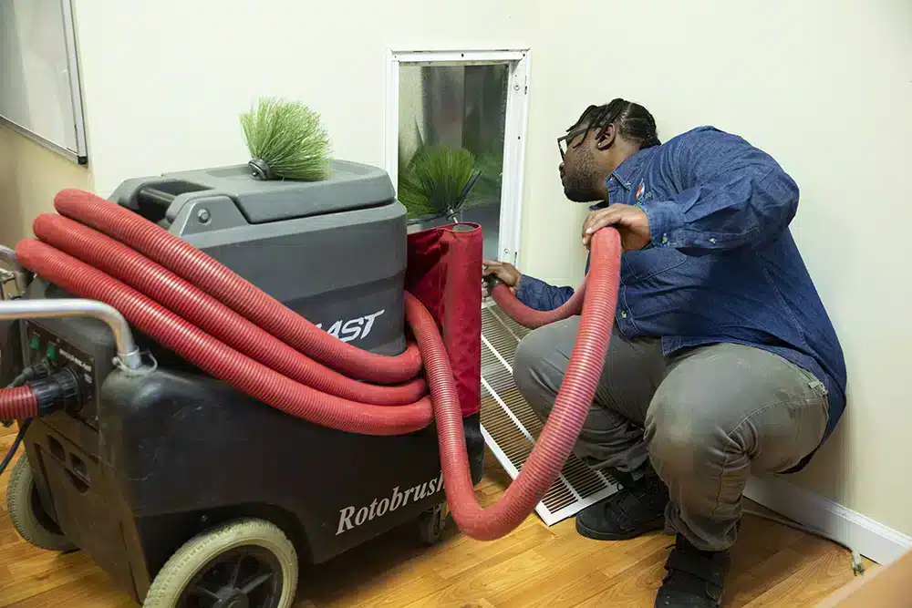 Absolute Heating & Air employee conducting duct cleaning services for homeowner in Morgantown, WV