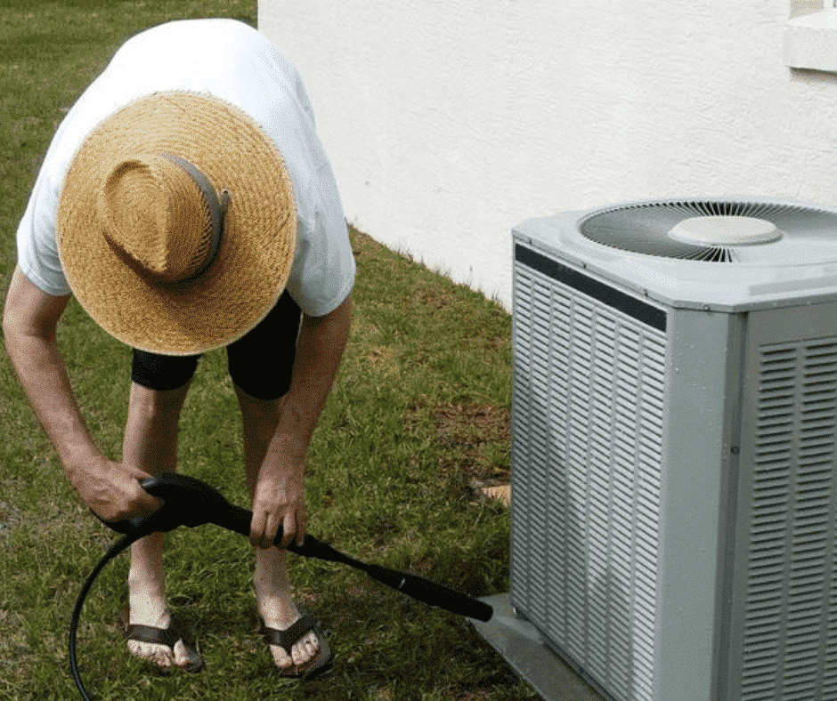person cleaning their outdoor AC unit