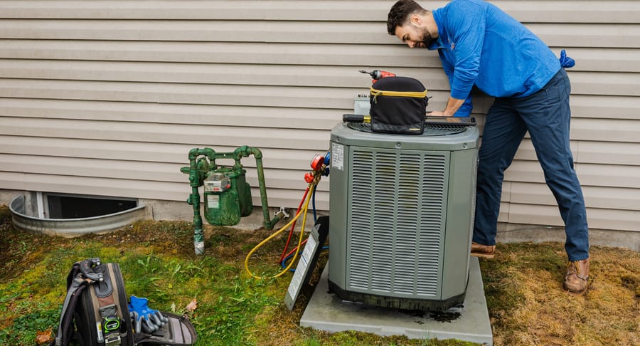 Technician conducting ac maintenance on an air conditioning unit.