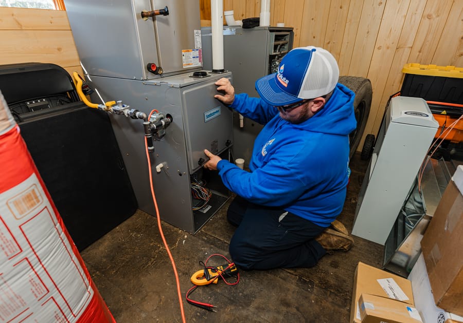 Technician kneeling in front of furnace.