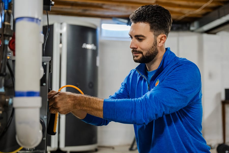 Absolute technician repairing heat pump in basement 