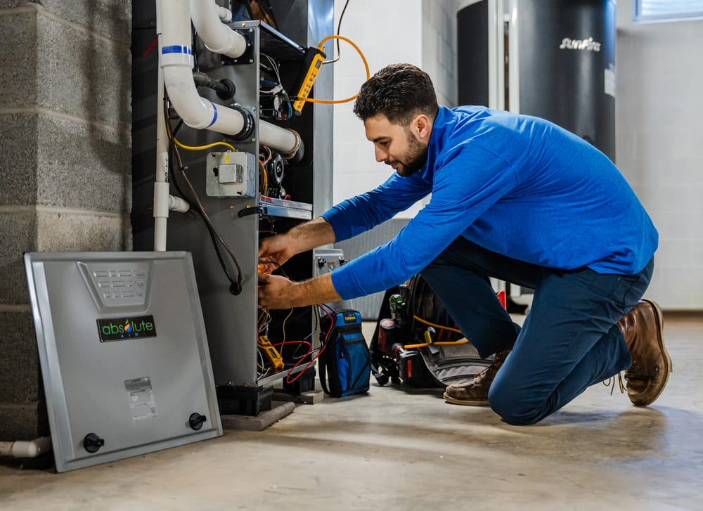 Absolute technician leaning over to conduct a heater repair to a heating system.