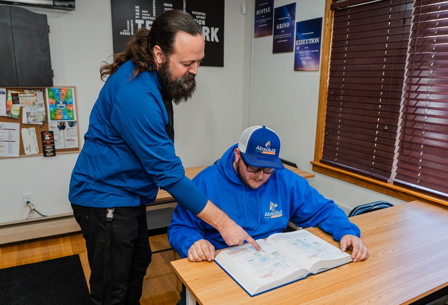 Two Absolute technicians examining the plans to a whole-home dehumidifier.