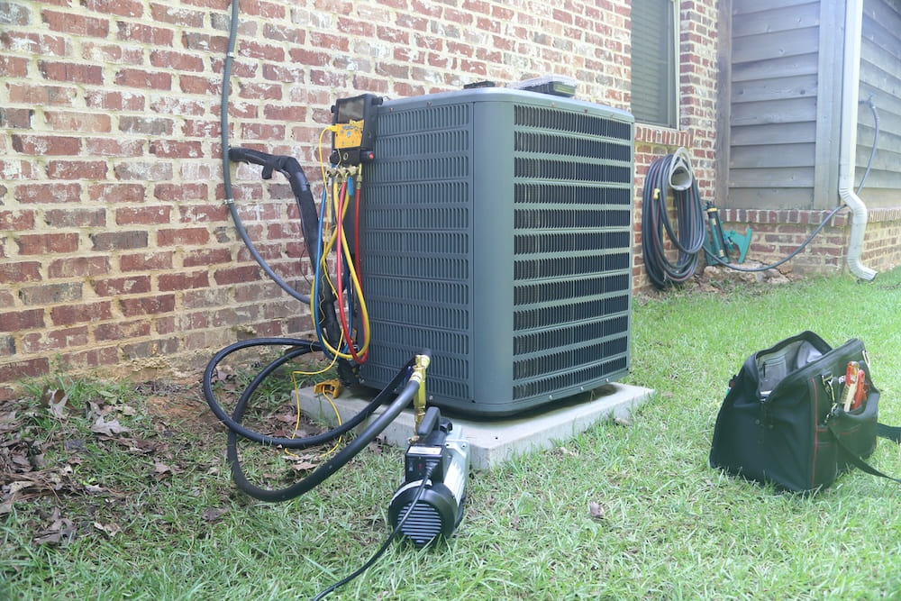 Outdoor air conditioning unit with toolbox on the grass in front of it