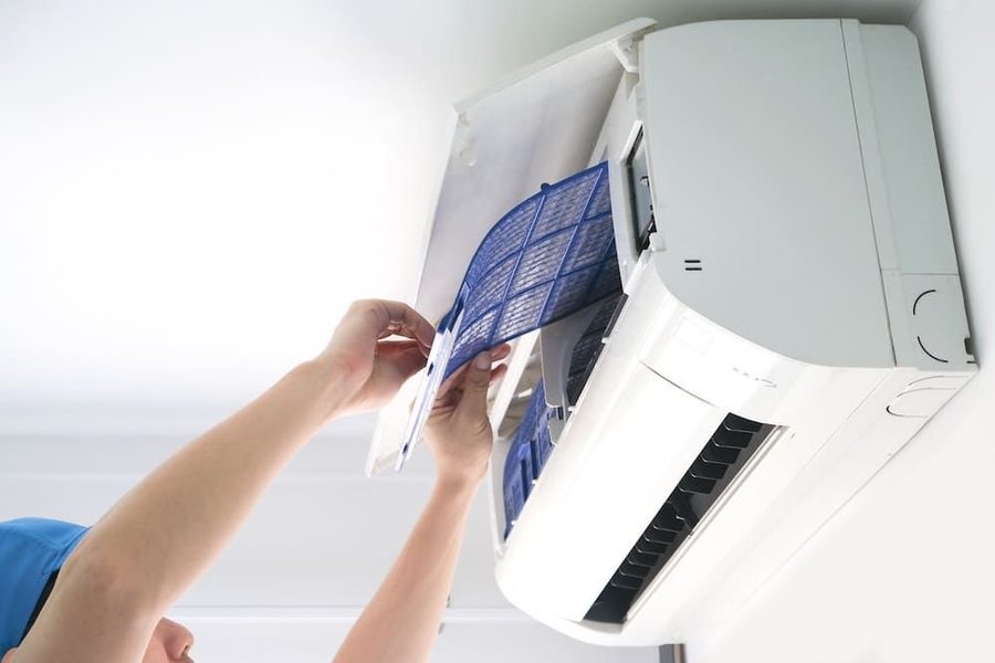 HVAC technician installing or repairing a ductless mini split mounted on the wall.
